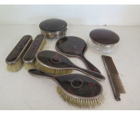 A tortoiseshell and silver dressing set consisting of hairbrushes, clothes brushes, hand mirror, comb, trinket box, cut glass