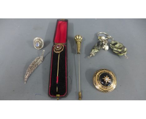 A mourning brooch of circular form, a white metal brooch of leaf design, a white metal and moonstone ring, two hat pins and a