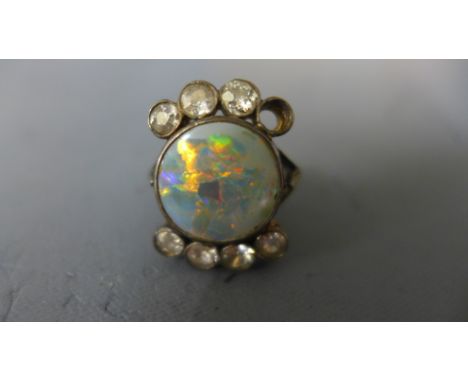 A yellow metal opal and diamond ring - the central circular opal flanked by seven diamonds each approx 0.125ct in size - one 