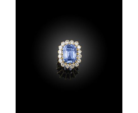 A sapphire and diamond cluster ring, the step-cut sapphire set within a surround of diamonds in yellow gold, size M Accompani