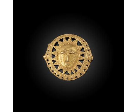     A modern West African gold sun circle pendant, centred with a face with scar decoration within two engraved sun ray surro