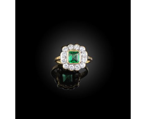 An emerald and diamond ring, of cluster design, collet-set with a step-cut emerald within a border of brilliant-cut diamonds,