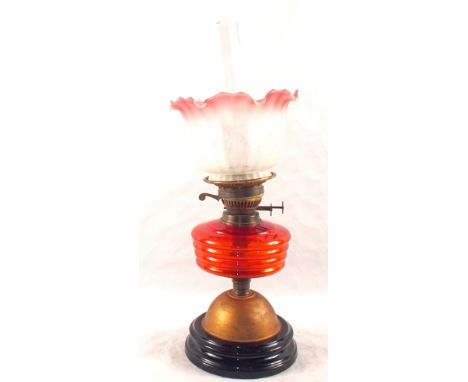 An oil lamp with red glass bowl and pink etched shade