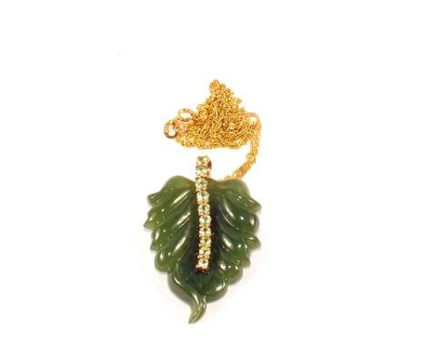 A carved Jade pendant in the form of a leaf mounted in 9ct Gold with a row of Peridots to centre, hung from a 9ct Gold chain