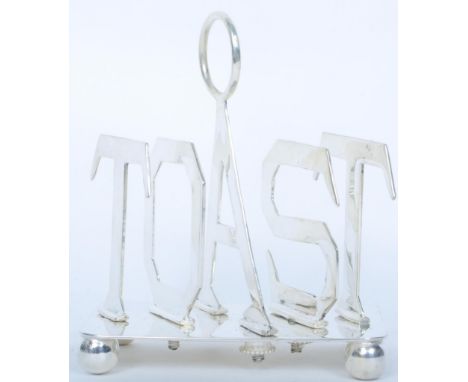 A vintage 20th century silver plated toast rack with ring handle and partitioning pieces spelling out 'toast', raised on bun 