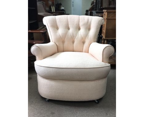 A peach patterned, button backed arm chair on casters.