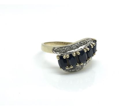 A 9ct yellow gold dress ring inset with a row of oval sapphires flanked by two rows of diamonds, ring size approximately L to