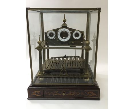 A Congreve mystery table clock raised on an inlaid wooden base fitted with a single drawer, complete with key and ball bearin