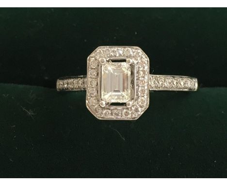 A quality 18ct white gold and diamond ring. The central Emrald cut stone approximately . 4 ct set in a raised mount surrounde