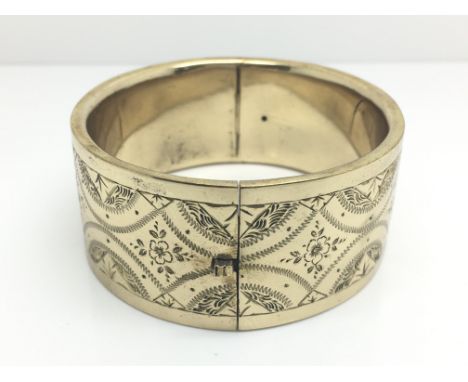 A Victorian gold tone bangle with floral decoration, approximate weight 42 grams.