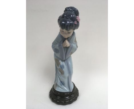 A Lladro figure of an oriental lady in traditional blue robes with pink blossom in her hair, approximately 26cm tall, with st