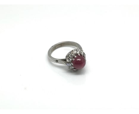 An 18ct white gold, diamond and cabochon ruby cluster ring, the central ruby stone circled by smaller diamonds, approximate r