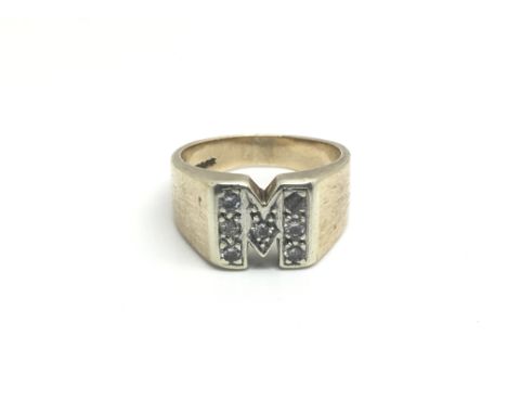 A 9ct yellow gold ring inset with diamonds in the shape of an M, total weight approximately 11 grams, ring size approximately