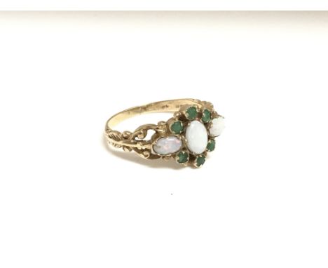 A ladies 9ct yellow gold ring inset with three oval opals circled by six small emeralds, total weight approximately 3 grams, 