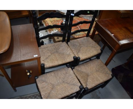 A pair of ebonised and rush seated ladder back chairs, and similar footstools
