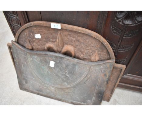 A vintage cast iron fireback with fleur de lys decoration and a cast canopy