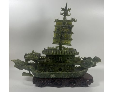 A CHINESE CARVED JADE TYPE GREEN HARDSTONE DRAGON DESIGN BOAT SCULPTURE ON WOODEN BASE, LENGTH 34CM 