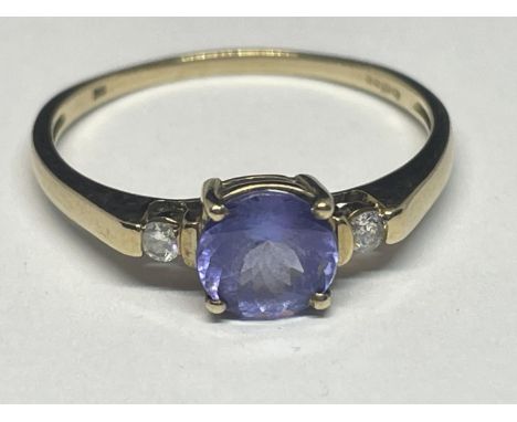 A 9 CARAT GOLD RING WITH A PURPLE GEMSTONE SURROUNDED BY TWO DIAMONDS SIZE R/S 