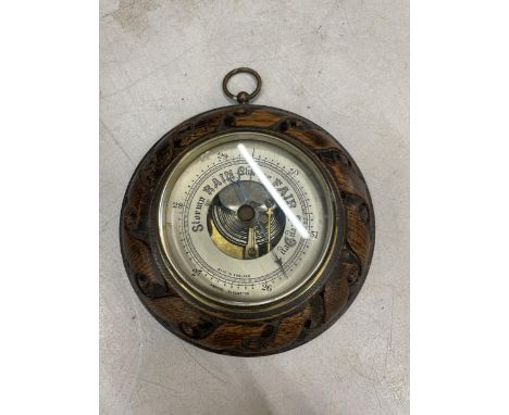 A CIRCULAR BAROMETER WITH A CARVED FRAME 
