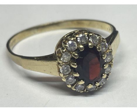 A 9 CARAT GOLD RING WITH CENTRE GARNET SURROUNDED BY CUBIC ZIRCONIAS SIZE R/S 