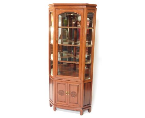 A 20thC Chinese hardwood corner cabinet, the upper section with glazed front and side panels, the polished top raised above t