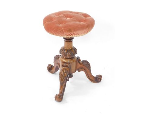A late Victorian walnut framed piano stool, with overstuffed button adjustable top, on a heavily carved stem terminating in t