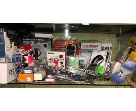 SHELF OF VARIOUS ITEMS INCLUDING CELL PHONE HOLDER, 4 IN 1 WIRELESS HEADPHONES, OPTICAL MOUSE, ADAPTERS               