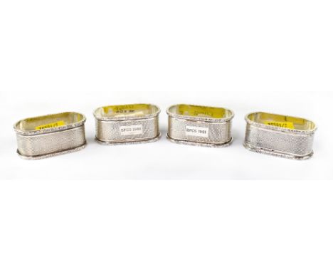 Four Elizabeth II hallmarked silver napkin rings of elongated form with raised floral rims and a central band of engine turne