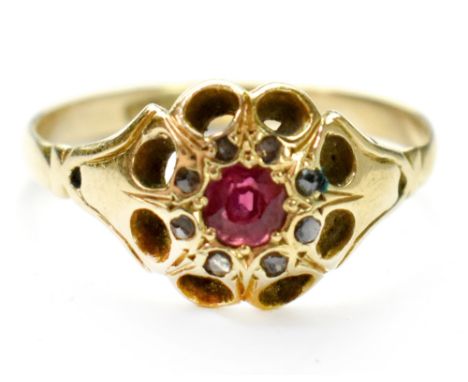 An 18ct gold ruby and diamond flower cluster ring, the central ruby within a halo of tiny diamonds within a pierced border, s