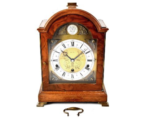 A Georgian-style walnut mantel clock by Syke &amp; Son, the silvered chapter ring set with Roman and Arabic numerals, on an e