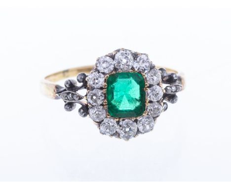 A Victorian emerald and diamond 18ct gold cluster ring, comprising a central claw set emerald cut emerald, approx 5 x 7mm, wi