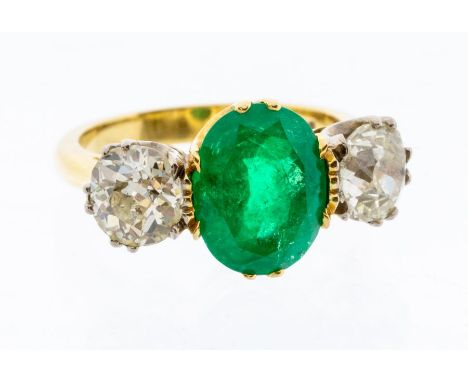 An emerald and diamond three stone 18ct gold ring, comprising an oval emerald approx 3.20 carats, with single old cut diamond