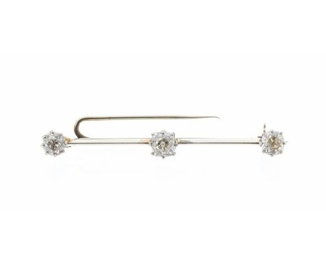 An early 20th Century diamond set white metal bar brooch, comprising three old cut diamonds, the central cushion cut diamond 