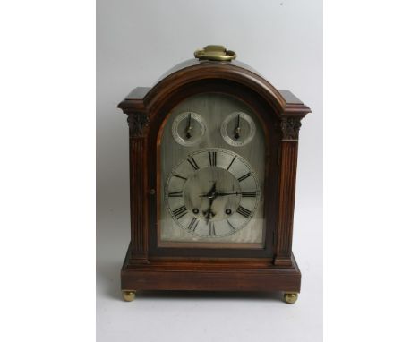 A mahogany cased mantle clock having arched silvered dial and Roman numerals