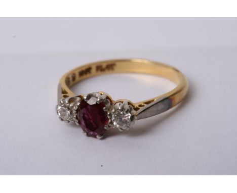 A ladies 18ct gold ring set with a central oval cut ruby flanked by diamonds
