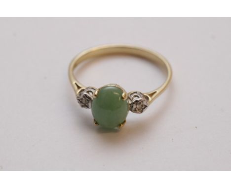 A ladies 9ct gold ring set with a central jade cabochon flanked by diamonds