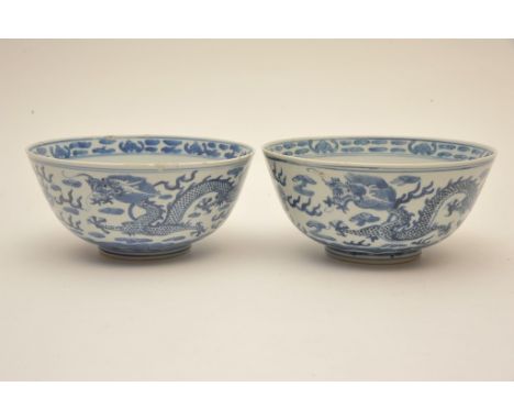 A pair of Chinese blue and white bowls decorated with dragons bearing Kangxi marks, some  damage