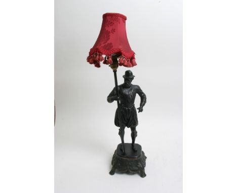 A metal table lamp in the for of a Spanish soldier supporting lamp fitting 