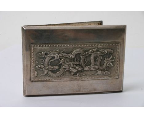 A white metal cigarette case with raised dragon