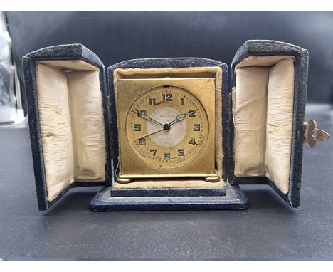 A small 1920s Zenith gilt metal alarm clock, 5.5cm high, in blue leather case. 