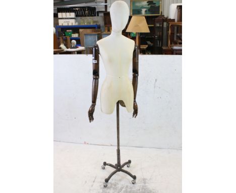 Female Shop Mannequin with cloth covered head and body, wooden articulated arms and hands, mounted on an industrial style met