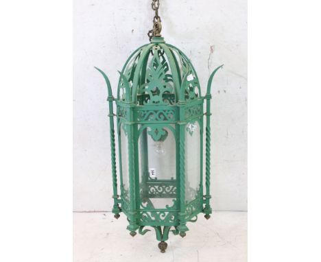 Green painted metal hanging lantern of a good size, the glass panels within a pierced fretwork frame and leaf decoration with