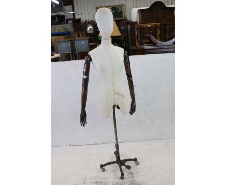 Female Shop Mannequin with cloth covered head and body, wooden articulated arms and hands, mounted on an industrial style met