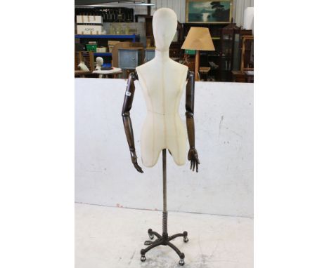 Female Shop Mannequin with cloth covered head and body, wooden articulated arms and hands, mounted on an industrial style met