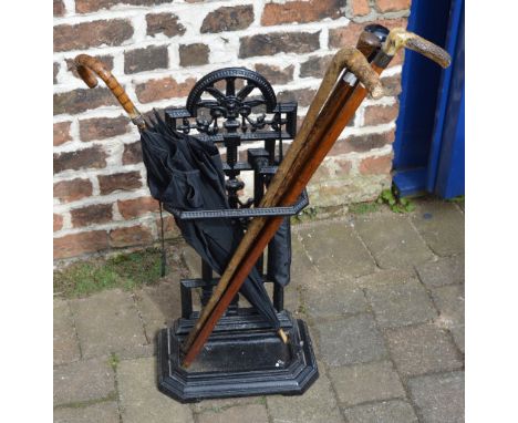 Cast iron stick stand & various walking sticks & an umbrella