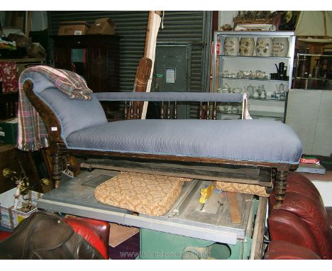 An Edwardian Chaise Longue, with scroll end cushions, padded back on spindle turned supports, carved show frame, on ring turn