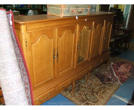 A large modern light Oak five door Cupboard on stand, moulded cornice over central glazed door with single bevel plated pane 