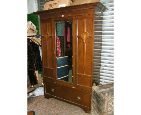 An Art Nouveau Oak single door Wardrobe, the moulded cornice having castellated detail over single bevel plate mirrored door,