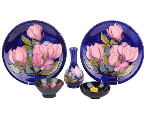 A pair of Walter Moorcroft circular pottery plates decorated with pink magnolia of a dark blue ground, one plate bearing a pa