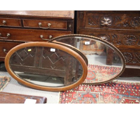 An Edwardian oval bevelled wall mirror, in line inlaid mahogany frame, and another oval mirror, in metal frame with bobbin de